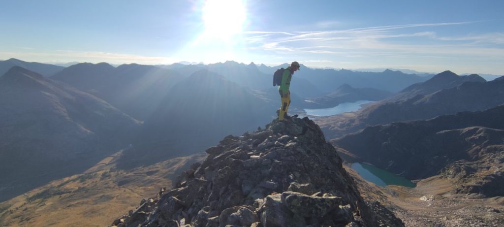 Trailrunner mit dem Raidlight Activ Legend Pack 24L im Geghenlicht auf einem Gipfel in den Bergen
