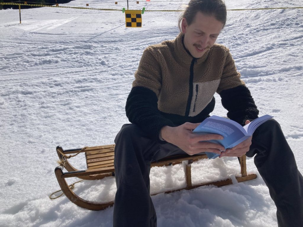 Vater beim Schlitteln im Schweizer Winter mit dem Winterkinder Schweiz Buch