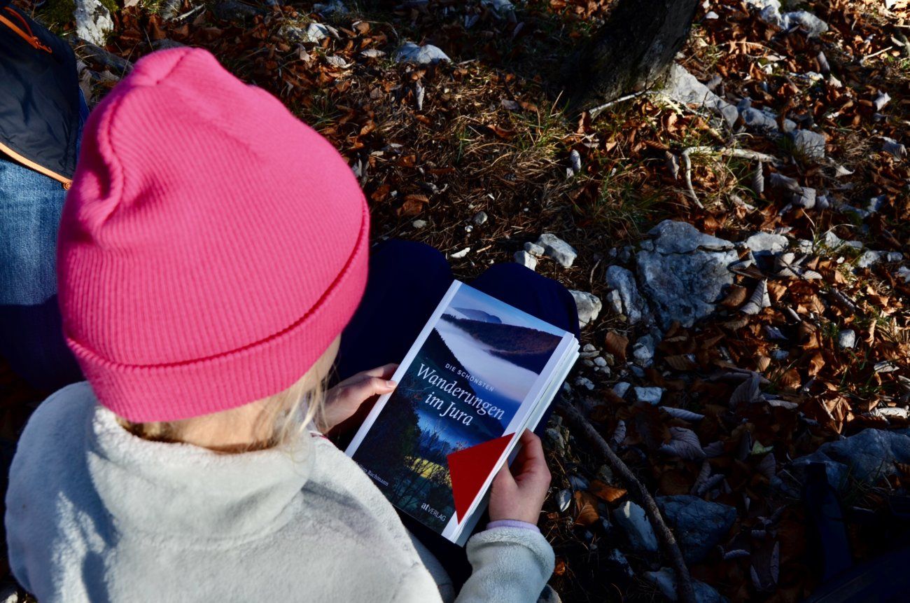 Kind im Wald mit Buchcover von Die schönsten Wanderungen im Jura Buch