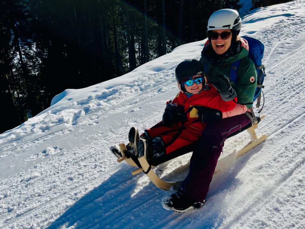 Kind im namuk Quest Skianzug beim Schlittelnfahren/Schlitteln