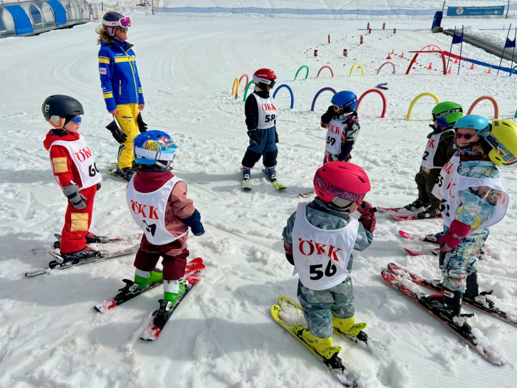 Kind im namuk Quest Skianzug beim Skifahren im Skikurs mit anderen Kindern