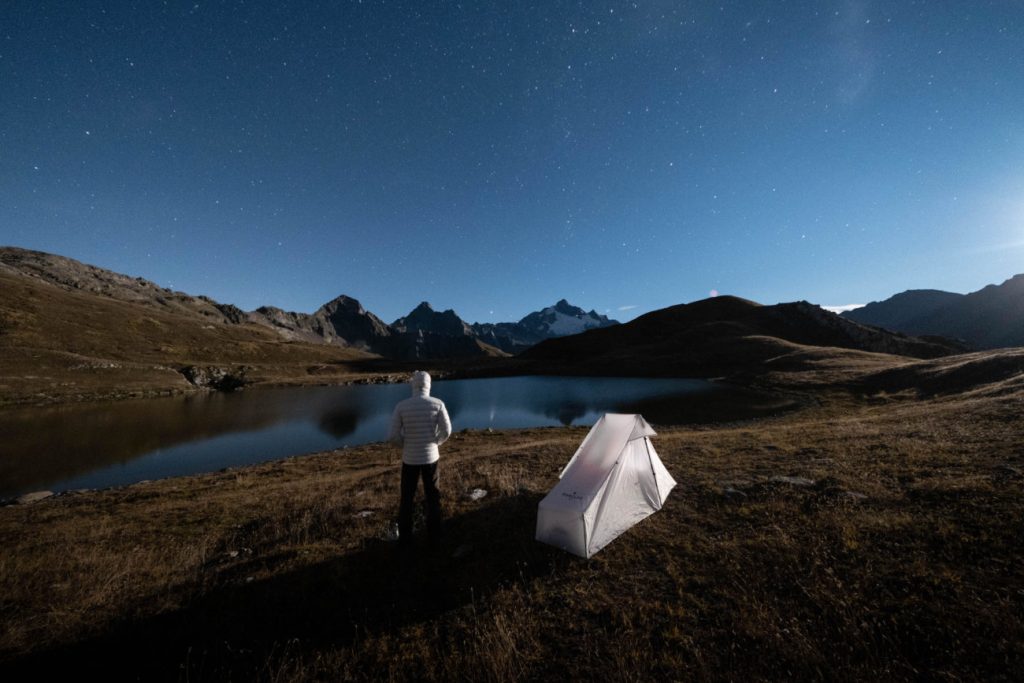 Wanderer mit FORCLAZ Tarp Tent an einem See unter Sternenhimmel