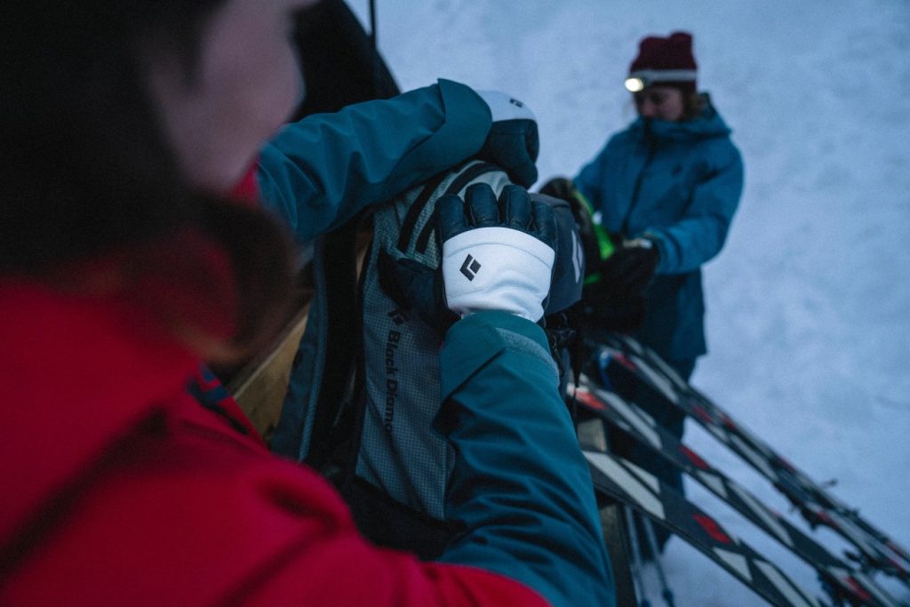 Skitourengeher mit Stirnlampe, Black Diamond Spark Gloves sucht etwas im Rucksack