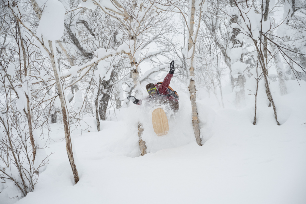 Snowboarder in tiefem Schnee zwischen Bäumen aus dem Film The Meaningless Pursuit of Snow