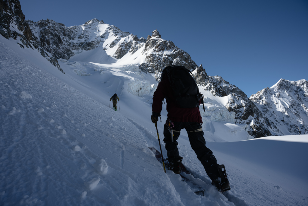 Berglandschaft mit Skitourengängern*innen auf steilem Hang aus dem Film The Meaningless Pursuit of Snow