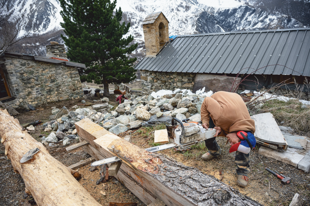 Handwerker schneidet Holz vor alter Hütte aus dem Film The Meaningless Pursuit of Snow