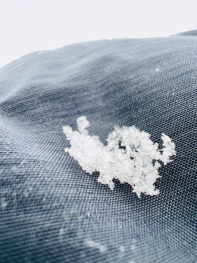 Detail: Schnee auf dem Gewebe der Rotauf Insulation Jacke 120 Herren mit Kapuze