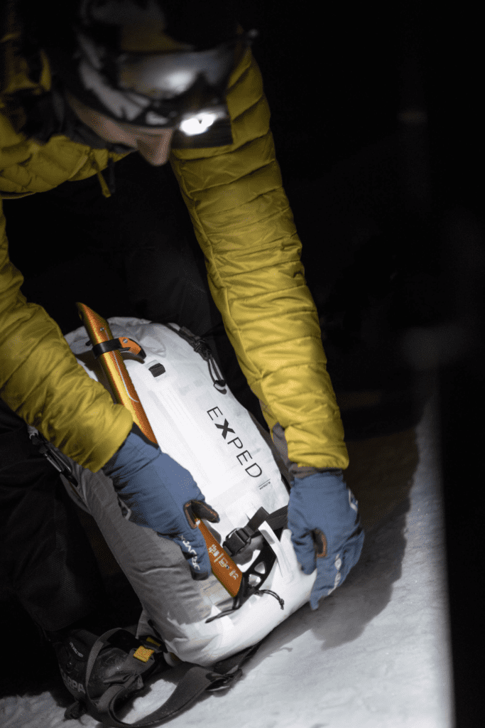 Bergsteiger befestigt Pickel am Exped Whiteout Alpinrucksack