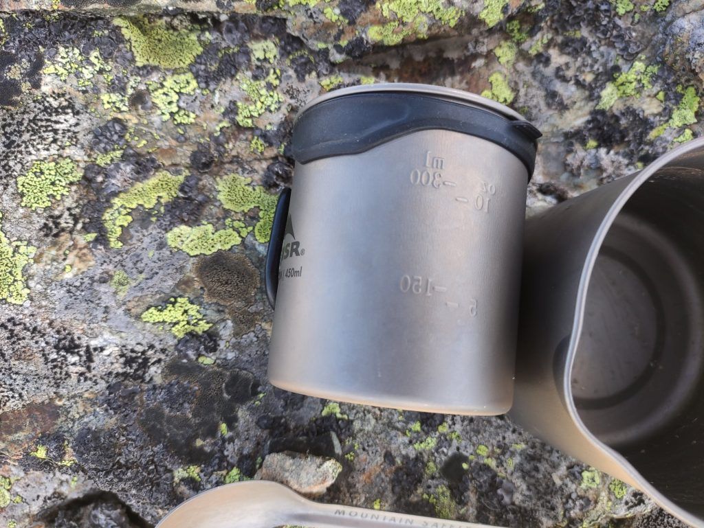 Nahaufnahme der MSR Titan Tasse mit Lippenschutz und gefaltetem Griff in der Natur