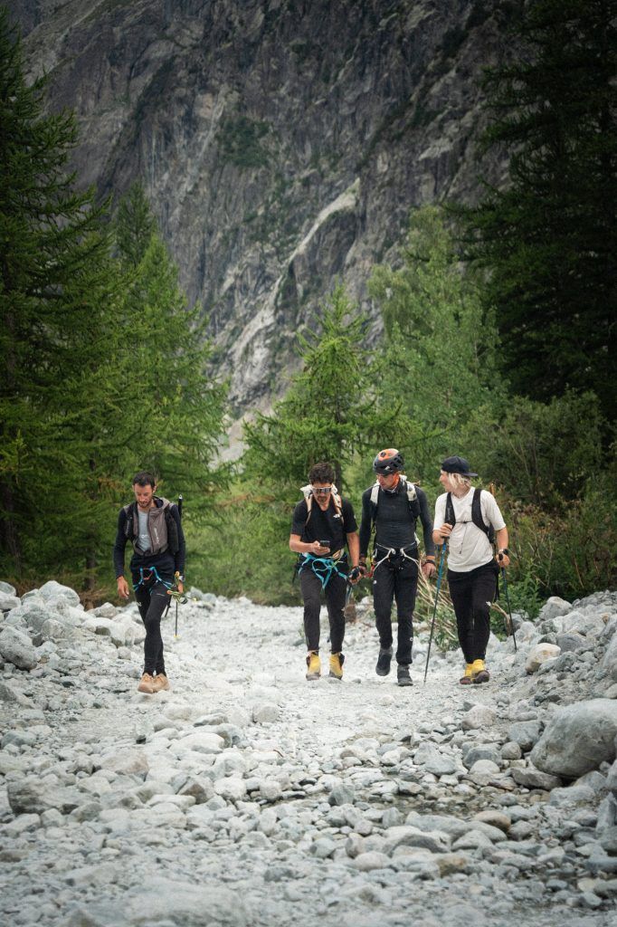 Vier Alpinisten auf einem steinigen Pfad während Kilian Jornet Alpine Connections in den Alpen.
