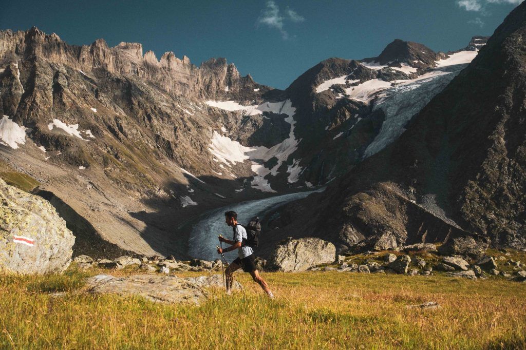 Kilian Jornet läuft durch eine alpine Wiese mit imposantem Bergpanorama während Kilian Jornet Alpine Connections.