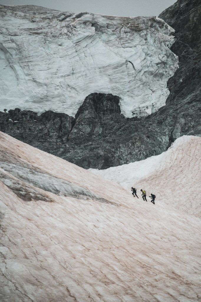 Drei Alpinisten steigen einen verschneiten Hang hinauf während Kilian Jornet Alpine Connections.