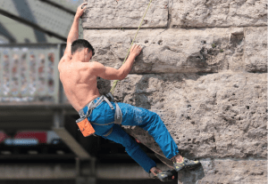 Mann bouldert in einer Indoor-Kletterhalle, vielfältige Optionen für einen Kletterurlaub in Genf.