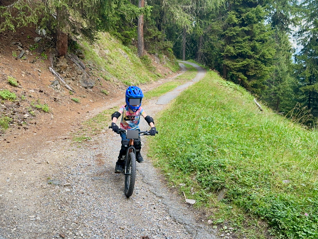Kind fährt das woom OFF 4 Mountainbike auf einem Waldweg, geniesst die Natur und das Abenteuer.