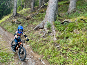 Kind fährt das woom OFF 4 über einen schmalen Pfad im Wald, zeigt Konzentration und Geschicklichkeit.