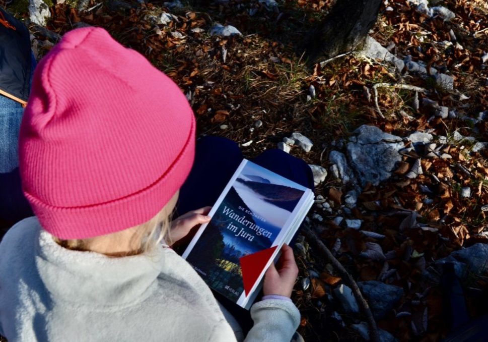 Kind im Wald mit Buchcover von Die schönsten Wanderungen im Jura Buch