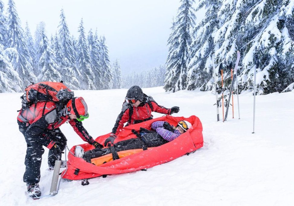 Ski patrol with rescue sled helping injured woman snow forest (KEYSTONE/CTK CANDYBOX/J.M. Guyon - Copyright 2013)